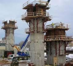 Multiple concrete columns under construction on a high-rise jobsite with crane support